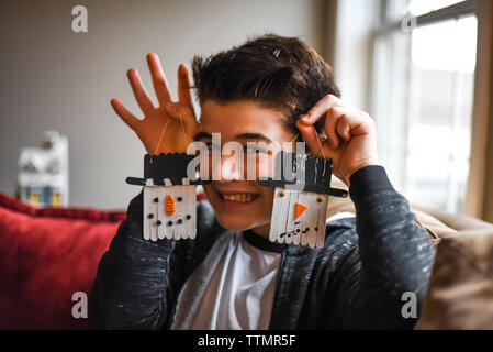 Close up of teenage boy holding two homemade snowman tree ornaments. Stock Photo