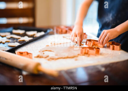 Close up of child's hands using cookie cutters on cookie dough. Stock Photo