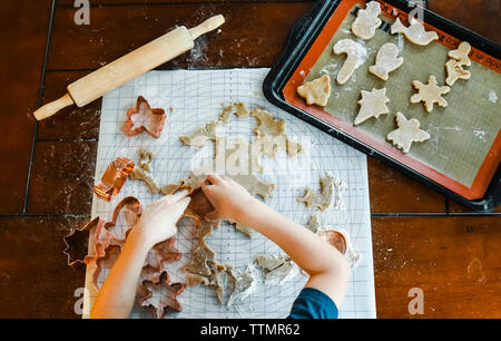Overhead shot of child's hands making cookies using cookie cutters. Stock Photo