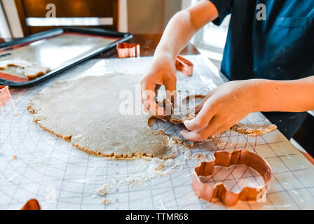 Close up of child's hands making cookies with cookie cutters. Stock Photo