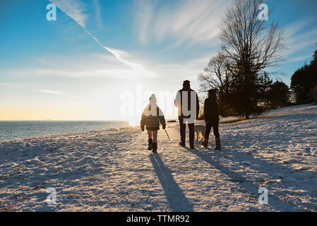 Silhouette of family walking along a snowy path at sunset. Stock Photo