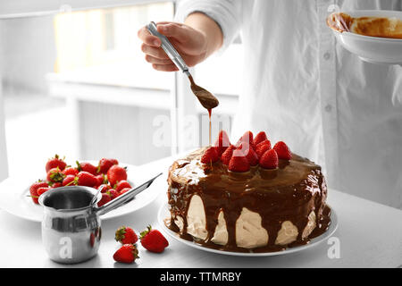 Female chef making caramel cake with strawberries Stock Photo