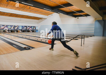 Older woman throwing bowling ball down a bowling lane. Stock Photo