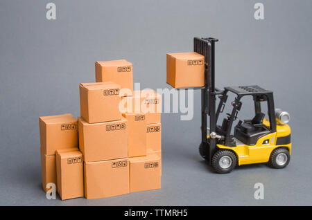 Forklift truck raises cardboard boxes on a yellow background. Cargo ...