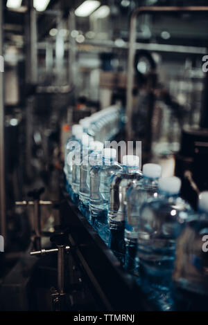 Close-up of water bottles in row on conveyor belt at factory Stock Photo