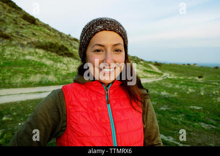 Portrait of cheerful young woman wearing jacket while standing on field Stock Photo