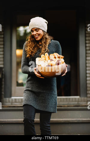 Happy woman carrying various breads in wooden bowl Stock Photo
