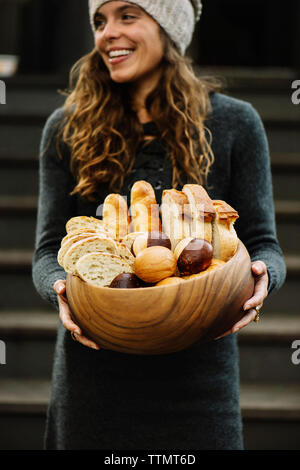 Happy woman with various breads in wooden bowl Stock Photo