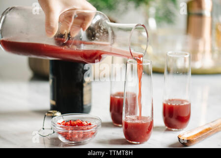 Cropped image of woman pouring juice in drinking glasses Stock Photo