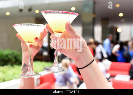 Cropped hands of female friends toasting martini glasses at restaurant Stock Photo