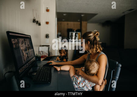 Working mother multitasking on the computer and holding baby Stock Photo