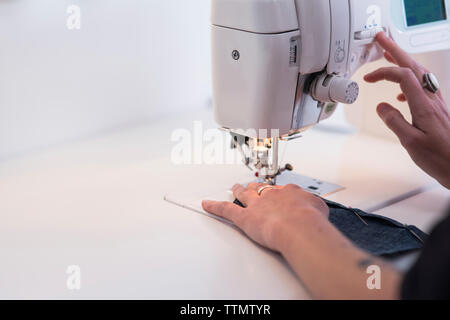 Cropped image of female tailor using sewing machine at table Stock Photo
