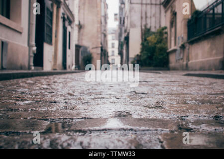 Wet empty alley amidst buildings in city during rainy season Stock Photo