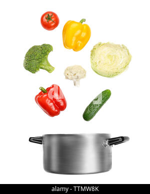 Fresh vegetables falling into a casserole pot on white background Stock Photo