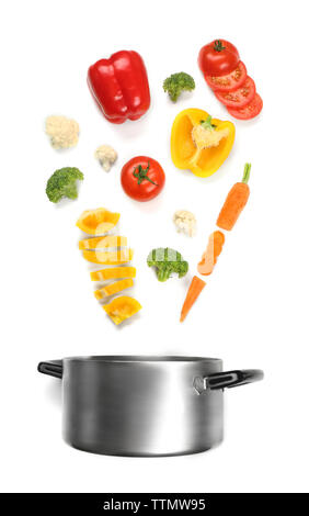 Fresh vegetables falling into a casserole pot on white background Stock Photo