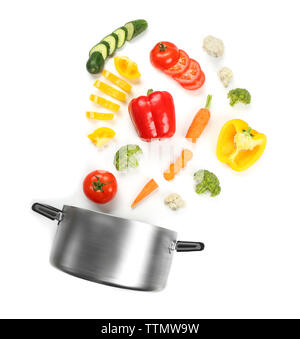 Fresh vegetables falling into a casserole pot on white background Stock Photo