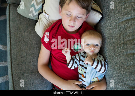 Overhead portrait of baby boy lying with sleeping brother on bed at home Stock Photo