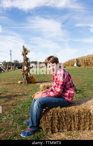 Close Up Tween Boy in Red Plaid Shirt Sitting on Hay Bale at Farm Stock Photo