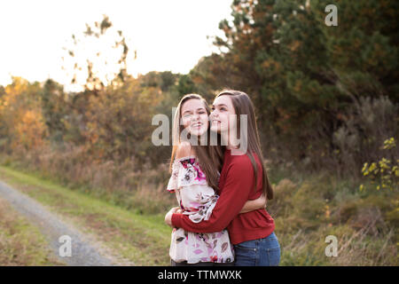 Teen Sisters Happily Hugging and Laughing on Trail at Sunset in Fall Stock Photo