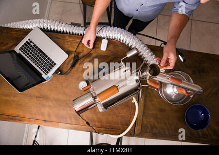 Overhead view of man using laptop and coffee roaster at table Stock Photo
