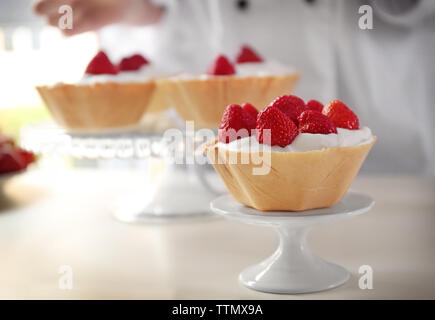 Female chef cooking tasty cakes with strawberries Stock Photo