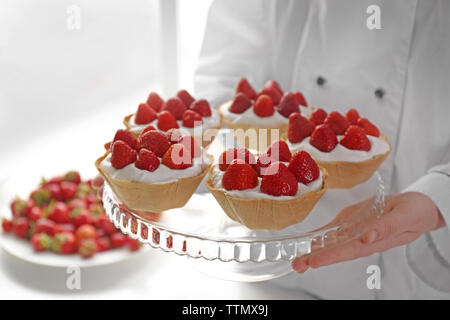 Female chef cooking tasty cakes with strawberries Stock Photo