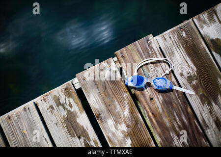 Overhead view of swimming goggles on boardwalk by lake Stock Photo