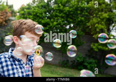Boy blowing bubbles in yard Stock Photo