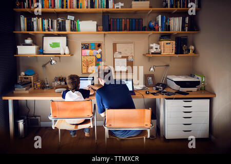 Father assisting son in using laptop computer at home Stock Photo