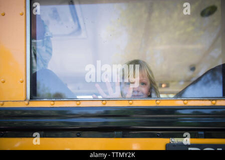 Portrait of girl looking through window while traveling in school bus Stock Photo