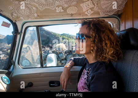 Thoughtful woman looking away while wearing sunglasses in camper trailer Stock Photo