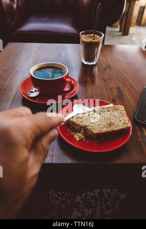 Cropped hand of man having bread with fork at cafe Stock Photo