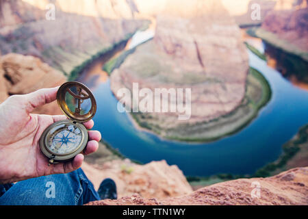 Low section of man holding navigational compass against Horseshoe Bend Stock Photo