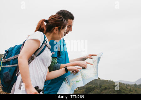 Friends analyzing map while standing against clear sky Stock Photo