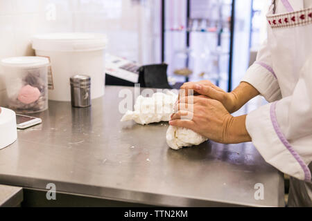 Midsection of female baker kneading dough on kitchen counter in laboratory Stock Photo