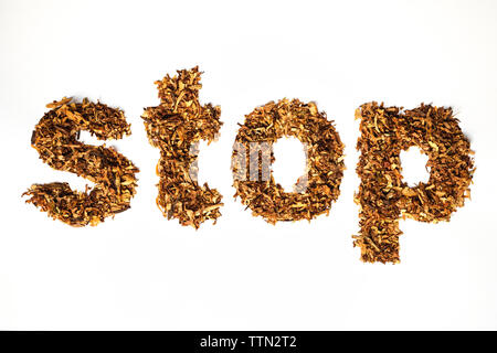 Frontal close up of the word STOP made of sliced cigarette tobacco on white background Stock Photo
