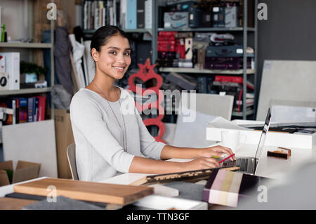 Portrait of happy interior designer working on laptop in office Stock Photo