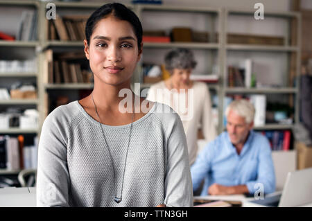 Portrait of confident interior designer standing in office with colleagues working in background Stock Photo