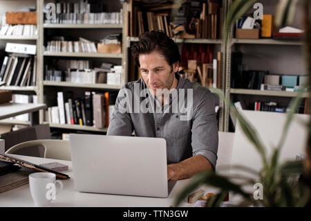 Male interior designer using laptop at desk in office Stock Photo