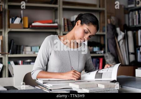Female interior designer writing in book at desk Stock Photo