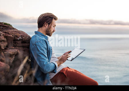 Side view of man using tablet computer by sea Stock Photo