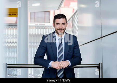 Portrait of confident businessman leaning on railing at subway station Stock Photo