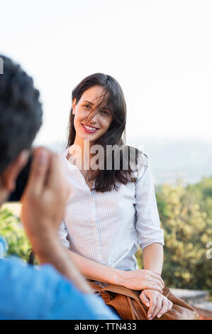 Cropped image of man photographing woman against clear sky Stock Photo