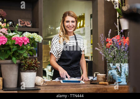 Portrait of smiling florist using tablet computer in shop Stock Photo