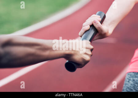 Cropped image of woman passing baton to teammate Stock Photo