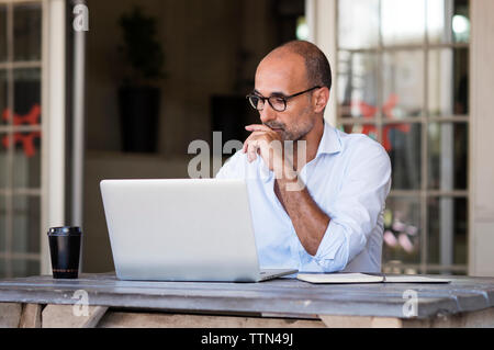 businessman using laptop computer while sitting at table in office Stock Photo
