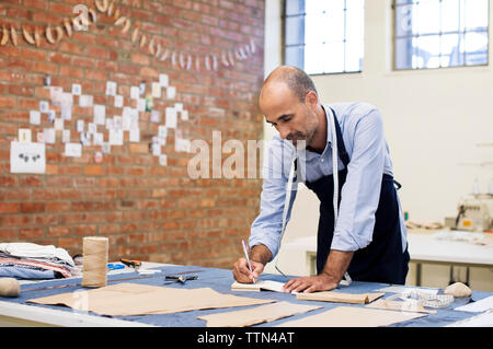 Male fashion designer working at table in workshop Stock Photo