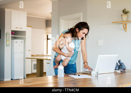 Woman using laptop computer while sitting with son at home Stock Photo