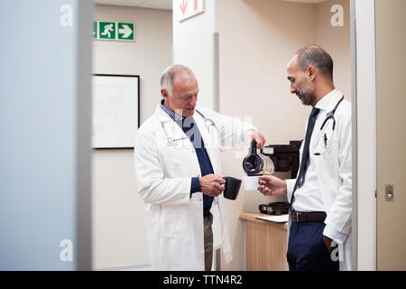 Doctors having coffee while standing in hospital seen through door Stock Photo