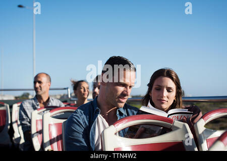 Passengers traveling in double-decker bus against clear blue sky Stock Photo